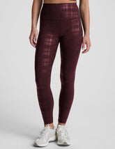 model wearing a plaid foil high-waisted midi leggings on a light gray background.